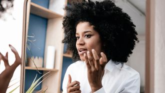 Vrouw kijkt in spiegel naar acne-littekens